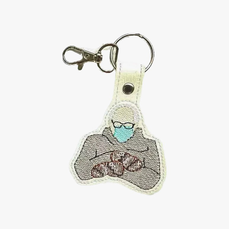 a keychain with an embroidered design depicting a person wearing a face mask.