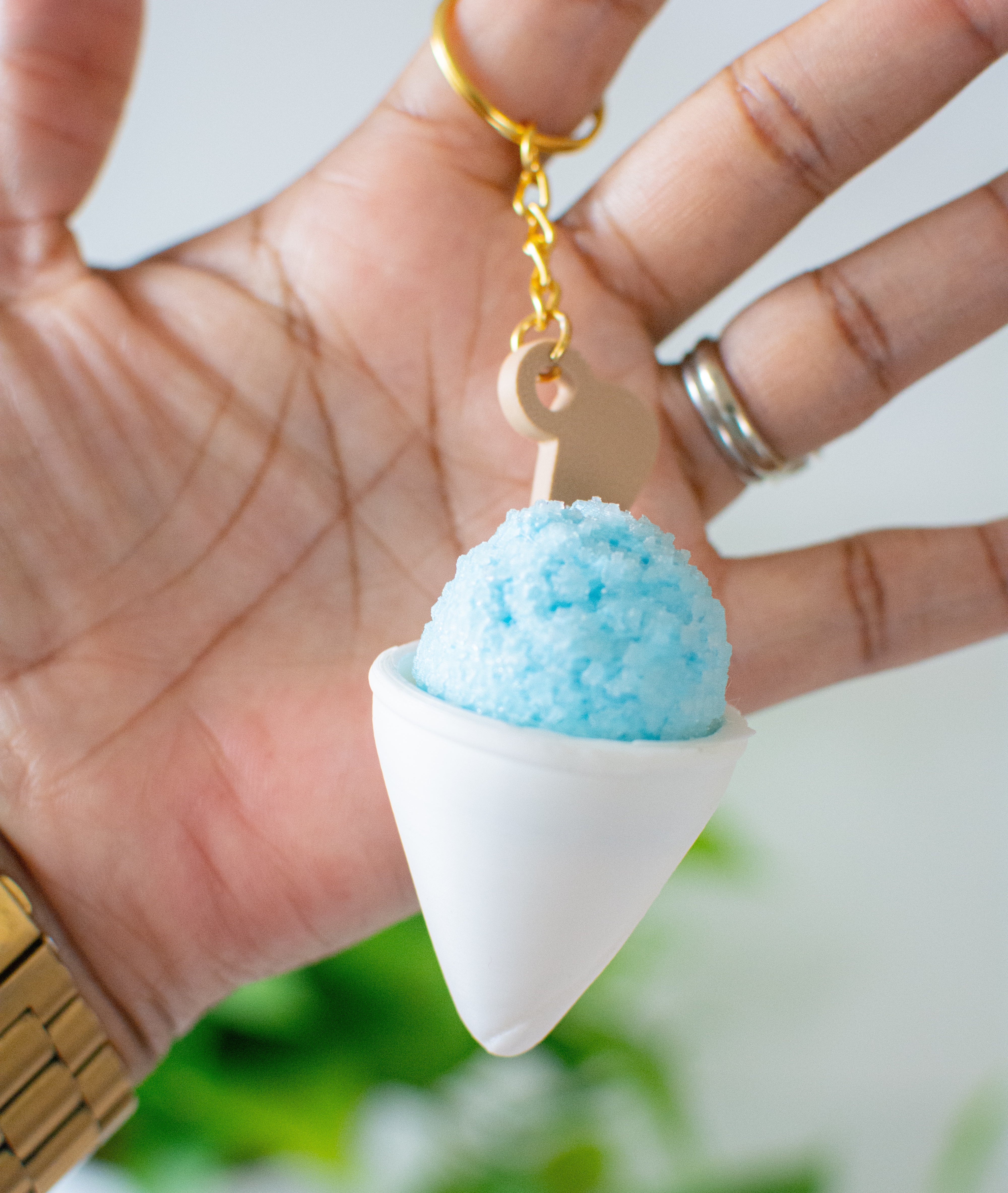 Keychain shaped like a cone with a blue top held in a hand against a blurred green background