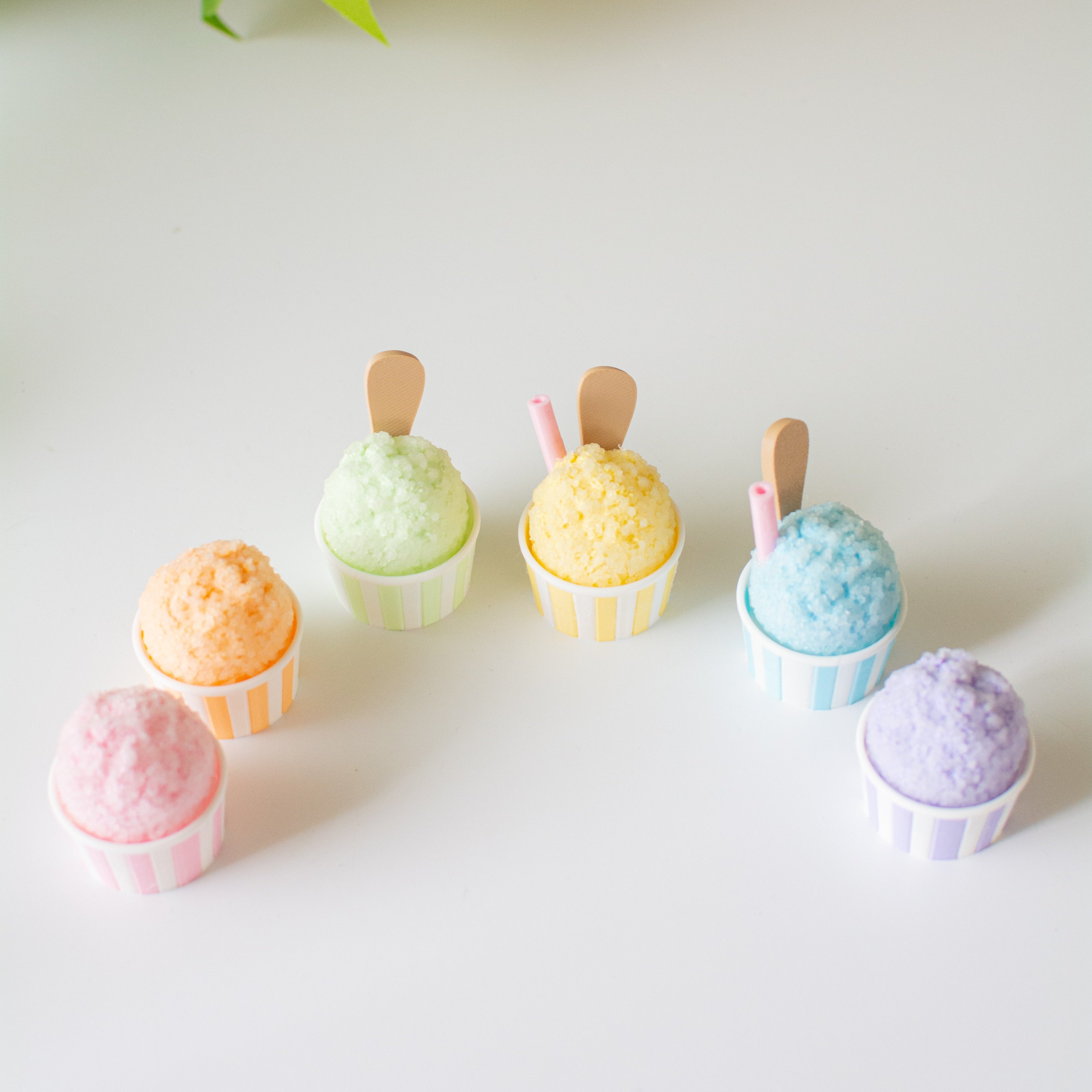 Colorful sno cones on a white surface with a plant in the background