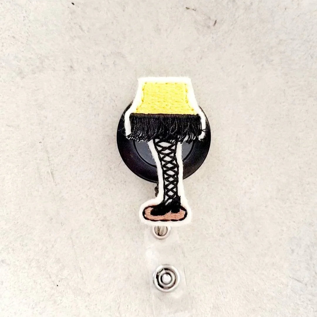 Embroidered badge reel with yellow lamp and black lace-up boot design, unique accessory