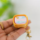 Small rectangular container with a yellow lid held by a hand against a blurred green background