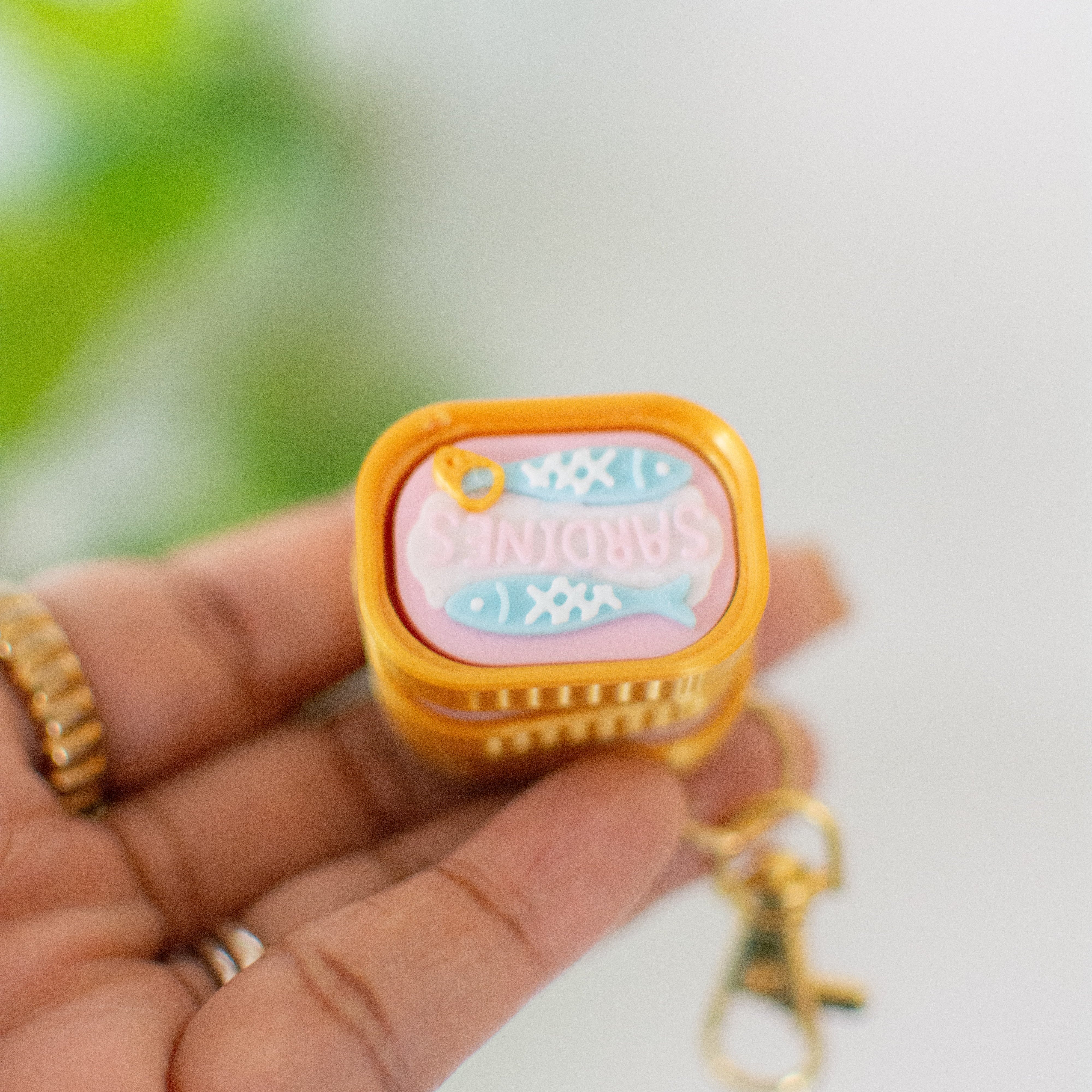 Small rectangular container with a yellow lid held by a hand against a blurred green background