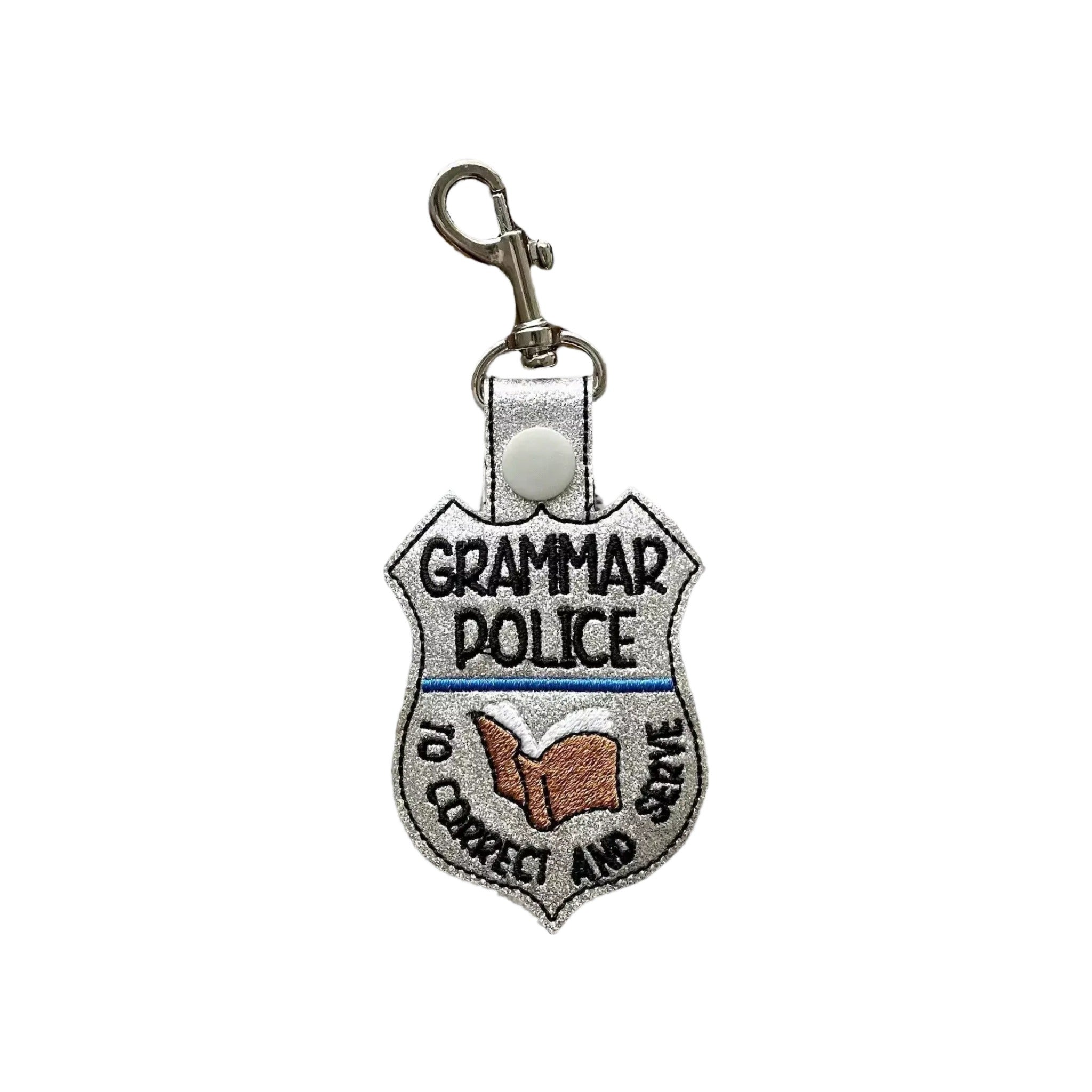 A keychain with a badge-like design, featuring the text "Grammar Police" and an image of a book.